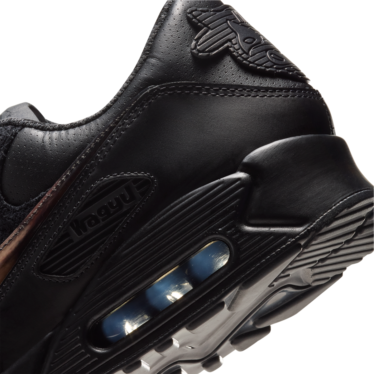 Close-up of a black leather sneaker showing the heel and midsole with a visible air cushion unit, on a plain white background. SIgned Wagyu