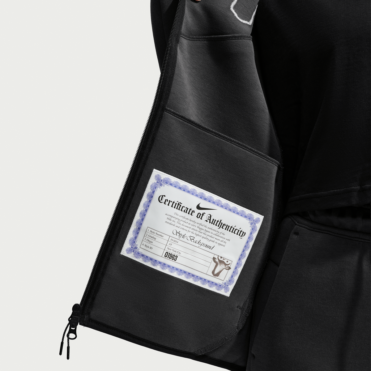 Close-up of the inside pocket of a black zip jacket showing a Certificate of Authenticity label from Nike.